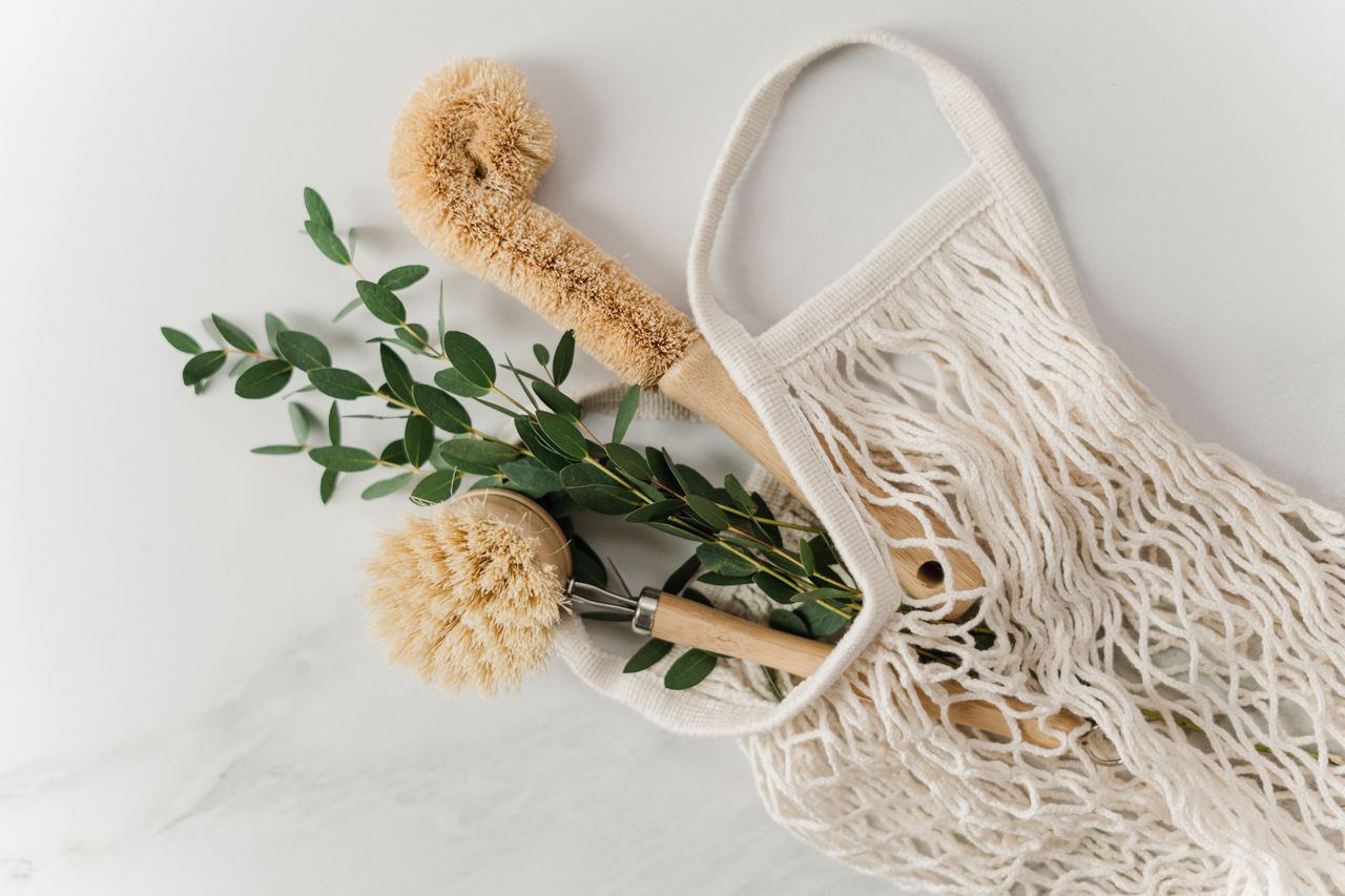 about-02 Eco-friendly cleaning brushes and eucalyptus branch in a net bag on a marble surface.